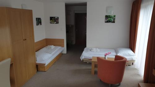 a room with two beds and a table and a chair at Penzión Dubo in Liptovský Mikuláš