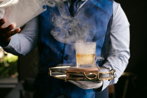 a man holding a tray with a glass of smoke at Seven Villa Hotel & Spa in Johannesburg
