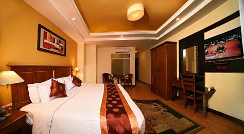 a hotel room with a bed and a flat screen tv at DOM Himalaya Hotel in Kathmandu