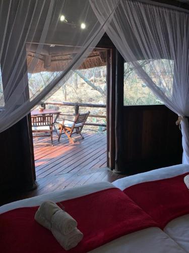 a bed in a room with a view of a deck at Shayamoya Tiger Fishing and Game Lodge in Pongola Game Reserve