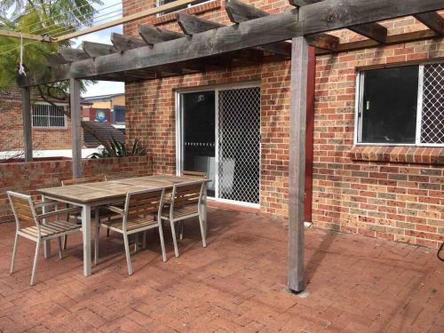 a wooden table and chairs on a brick patio at Cozy 3BR Townhouse in Liverpool CBD with parking in Liverpool