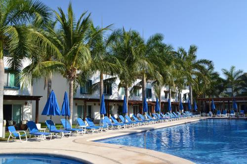 una piscina con sedie, ombrelloni blu e palme di EXCLUSIVA VILLA EN LA ZONA HOTELERA DE IXTAPA_ZIHUATANEJO a Ixtapa