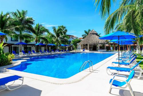 a swimming pool with blue chairs and umbrellas at Villa exclusiva en Ixtapa a unos pasos del mar in Ixtapa