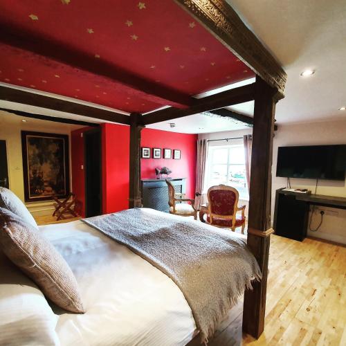 a bedroom with a large bed with a red wall at The Old Lodge in Stroud