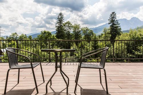 two chairs and a table on a deck with mountains at Royal Hill Residence in Zakopane