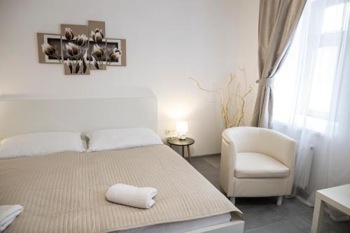 a white bedroom with a bed and a chair at Rezidence Černý medvěd in Znojmo