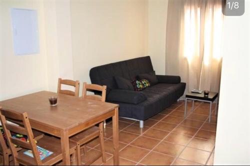 een woonkamer met een zwarte bank en een tafel bij Apartamentos Turisticos Rurales El Pua in Cazalla de la Sierra