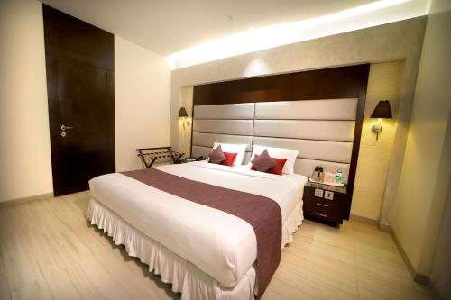 a bedroom with a large white bed with a large headboard at Southern Plaza in Kolkata