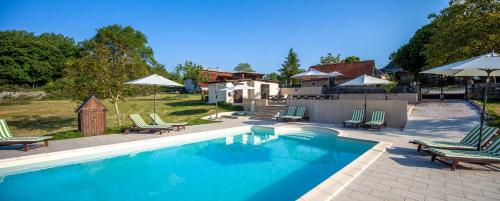 une piscine avec chaises et parasols dans une cour dans l'établissement Chambres et table d'hôtes La Panacée, à Cuzance