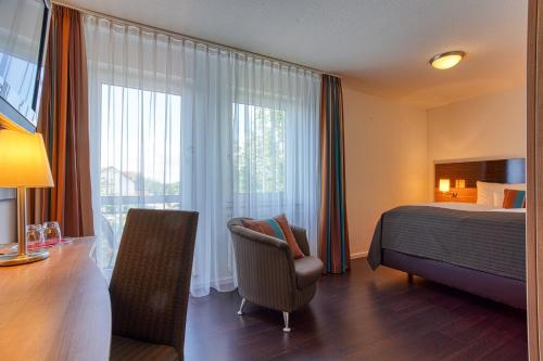 una camera d'albergo con letto, sedia e scrivania di Centro Hotel U-NO 1 a Großbettlingen
