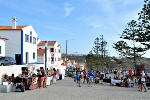 a group of people walking down a street with a crowd at Our Sunset Spot in Zambujeira do Mar