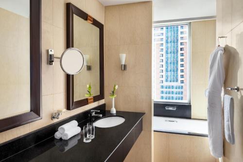 baño con lavabo, espejo y ventana en Shangri-La Apartments, en Dubái