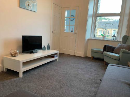 a living room with a flat screen tv on a table at River Teviot Apartment in Hawick