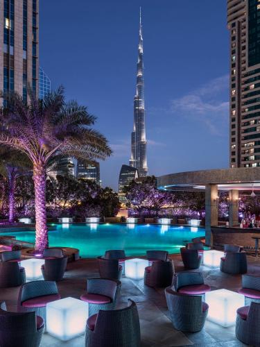 a pool with chairs and a city skyline at night at Shangri-La Apartments in Dubai