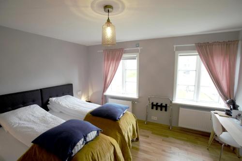 a bedroom with two beds and a desk and windows at Brimslóð Atelier Guesthouse in Blönduós