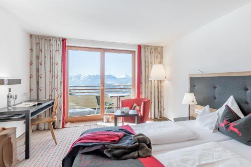 Habitación de hotel con cama, escritorio y ventana en Inntaler Hof, en Seefeld in Tirol