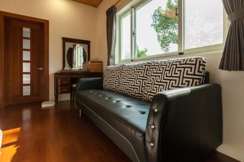 a black leather couch in a living room with a window at Countryside B&B in Ruisui
