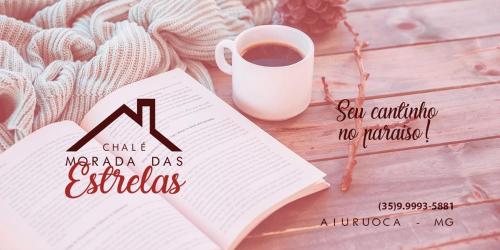 a book and a cup of coffee on a wooden table at Chalé Morada das estrelas in Aiuruoca