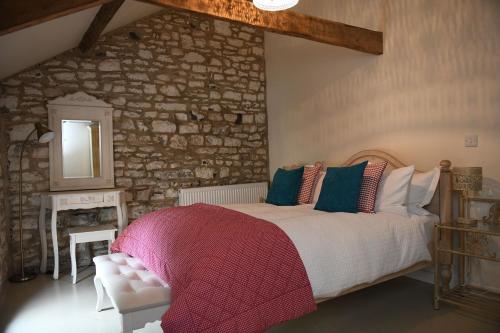 1 dormitorio con cama y pared de piedra en The Stable Loft, Llwynhelig Manor en Llandeilo