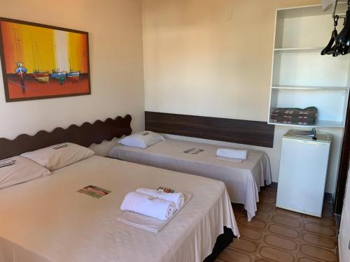 a room with two beds and a refrigerator at Pousada Paradise in Alcobaça