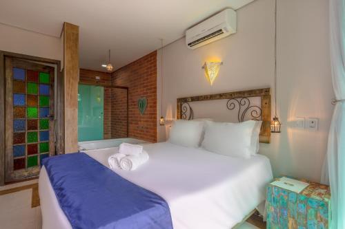 a bedroom with a large white bed and a window at Hotel Vila Kebaya in Ilhabela