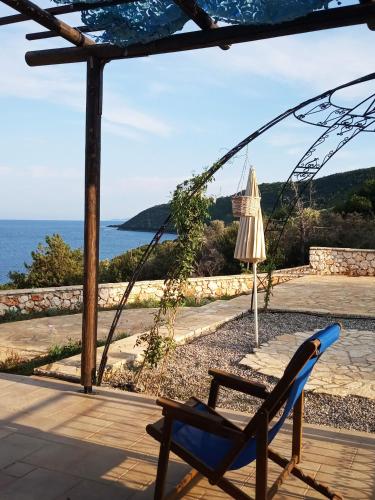 a patio with a chair and an umbrella and the ocean at Villa LeSunLuka Lefkada in Vasiliki