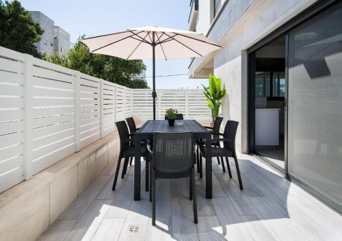 a table and chairs on a balcony with an umbrella at Balfour sea view city center in Nahariyya
