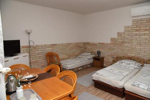 TolnaにあるSzilvia Panzióのベッド3台、テーブル、椅子が備わる客室です。