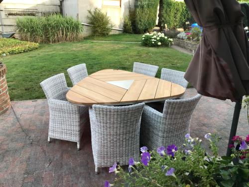 a wooden table with wicker chairs around it in a yard at Ferme de la Petite Fagne in Spa