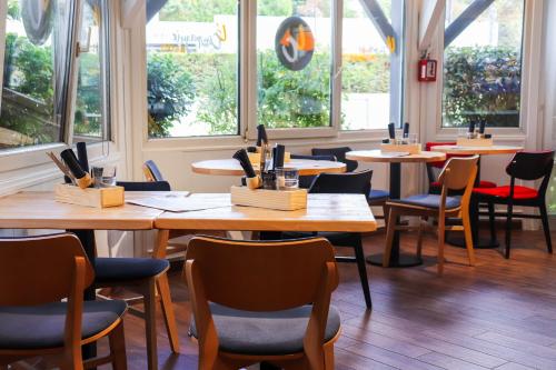 a restaurant with wooden tables and chairs and windows at ibis Nogent Sur Marne in Nogent-sur-Marne