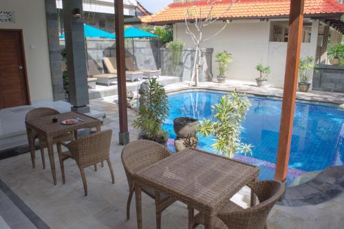una piscina con mesas y sillas junto a una casa en Flamboyan Hotel, en Kuta