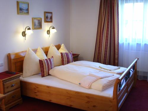 a bedroom with a bed with white sheets and pillows at Pension Heidi in Kaprun