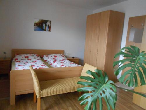 a bedroom with a bed and a chair and a plant at Weingut zur Schlafmütze in Herrnbaumgarten