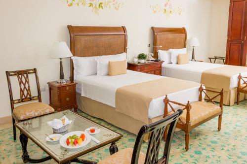 a hotel room with two beds and a table at Mansión Mérida Boutique Hotel - Restaurant in Mérida