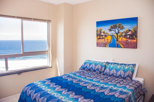 a bedroom with a bed and a painting on the wall at High Tide in Amanzimtoti