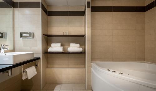 a bathroom with a sink and a tub and towels at Domaine du Gouverneur, Hôtel, Restaurant & Golf in Monthieux