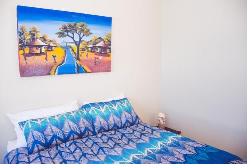 a bedroom with a bed with a painting on the wall at High Tide in Amanzimtoti