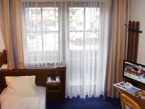 a bedroom with a bed and a window with curtains at Pension Heidi in Kaprun