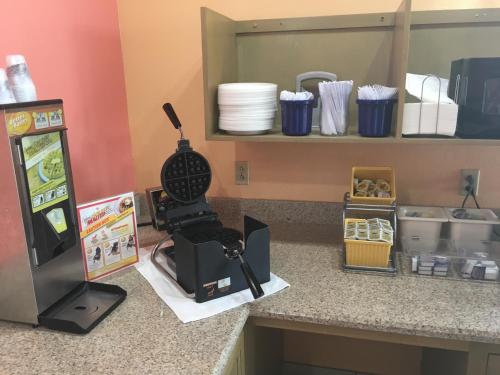 a kitchen counter with a coffee maker next to a refrigerator at Days Inn by Wyndham Hattiesburg MS in Hattiesburg