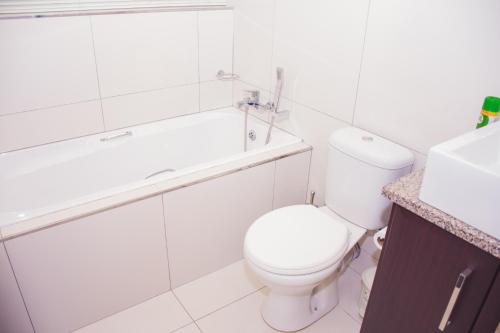 a bathroom with a toilet and a tub and a sink at High Tide in Amanzimtoti