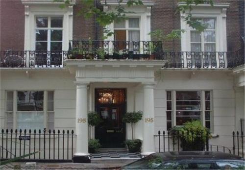 a large white house with a door and a balcony at Rhodes Hotel in London
