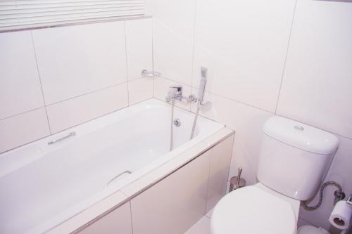 a white bathroom with a tub and a toilet at High Tide in Amanzimtoti