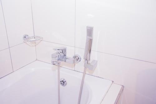 a shower with a hose in a white bathroom at High Tide in Amanzimtoti