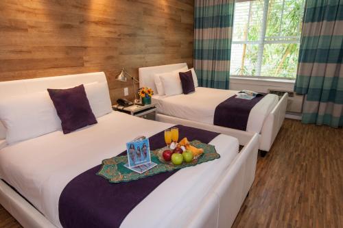 duas camas num quarto de hotel com uma bandeja de frutas em Shelley Hotel em Miami Beach