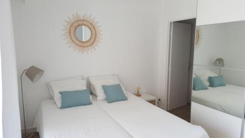 - un lit blanc avec des oreillers bleus et un miroir dans l'établissement Port la Gavine vue mer, à Hyères