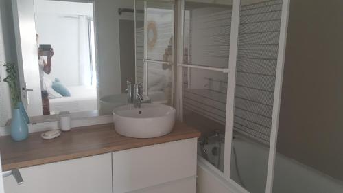 une salle de bain blanche avec un lavabo et un miroir dans l'établissement Port la Gavine vue mer, à Hyères