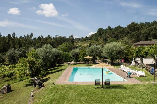 a swimming pool in a grassy field with trees at Quinta Do Meira in Braga