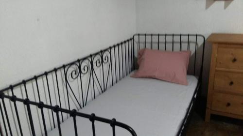 a metal bed with a pink pillow on it at villa athos in Sarti