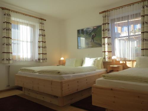 two beds in a bedroom with two windows at Tuschnhof in Rinn