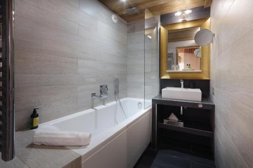 a bathroom with a tub, sink and mirror at Hotel Des 3 Vallées Val Thorens in Val Thorens
